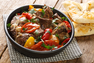 Delicious buglama meat stewed with vegetables and herbs in its own juice close-up in a bowl on a wooden table. horizontal