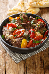 Caucasian cuisine Buglama lamb stewed with vegetables and herbs close-up in a bowl on a wooden table. vertical