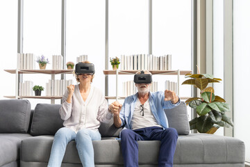Obraz premium senior couple having fun together with virtual reality headset on the sofa