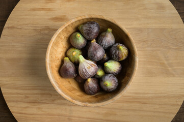 Top view figs in wooden bowl on wooden table, with copy space. High quality photo