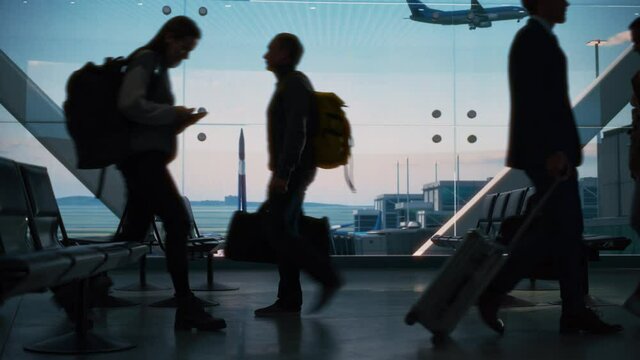 Busy Airport Terminal: Diverse Multi-Ethnic Crowd of People Walking, Hurry or Wait for their Flights. People Sitting in a Boarding Lounge of Big Airline Hub with Airplanes Departing and Arriving