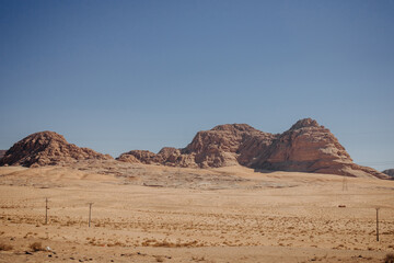 Plakat A picturesque mountain in the desert. Desert Wadi Rum with red sand. Landscape by the road. Jordan