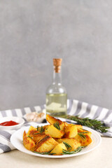 Fried potatoes with garlic and rosemary in a white plate. Copy space. Selective focus. Vertical photo.