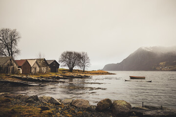 Norwegian fjord ethereal landscape with boat houses and old rocks on the beach