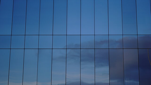 clouds reflected in building glass facade