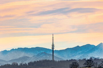 Obraz premium Transmission tower near Hohenpeissenberg in Bavaria against a slightly blurred backdrop of the Ammergau Alps in pastel colors