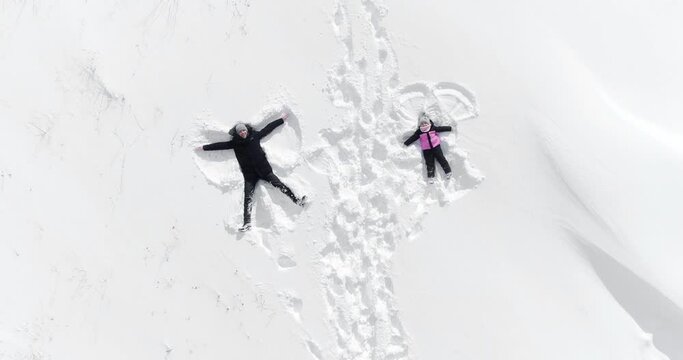 happy family woman and man lies in the snow and makes an angel