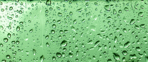 abstract water drops on a glass with green background.