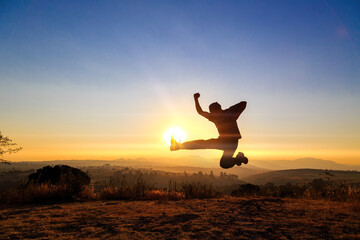 man performing flying kick on a blurred surface that looks like a mountain at sunset © Nailotl