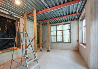 Interior of apartment during construction, remodeling, renovation, extension, restoration and reconstruction - ladder and construction materials in the room