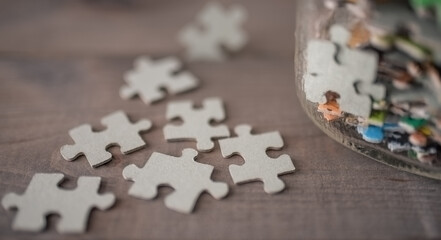 Puzzle pieces near glass on wooden background
