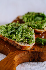 Mashed  avocado on toasted bread on cutting board served with cilantro