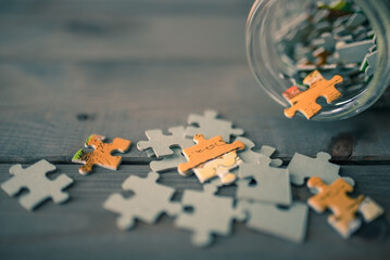 puzzle pieces spilling from glass jar on wooden background
