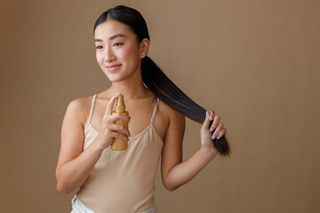 Asian young woman applying hair spray on her ponytail