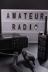 Closeup of pair of mobile two-way radios for Amateur radio operators against dark background.
