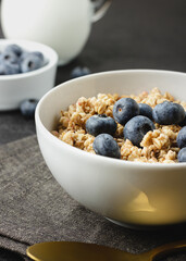 Granola with blueberry in bowl on dark napkin.