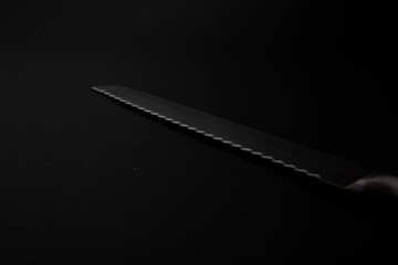 Knives made of metal, silver, lie on a black background with a glare of light