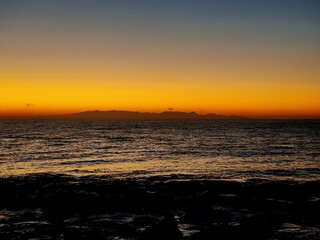 Isla en el horizonte y cielo anaranjado