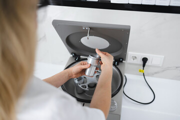 Doctor beautician puts a test tube in a metal container. Preparation for the plasmolifting procedure