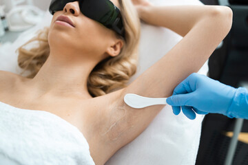 Obraz na płótnie Canvas Applying a transparent gel before the laser hair removal procedure to the armpit area. Underarm epilation process