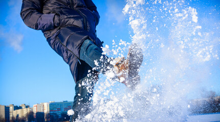 A man in brown boots kicks the snow. Winter fun in the snow. Snow is falling from under my feet.