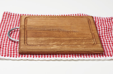 empty rectangular wooden kitchen cutting board and red towel in a white cage on a white table, top view