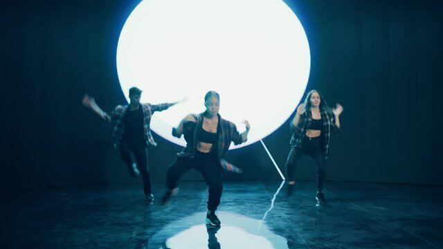 Diverse Group of Three Professional Dancers Performing a Hip Hop Dance Routine in Front of a Big Led Wall Screen with VFX Animation During a Virtual Production in Studio Environment. 105 BPM Song.