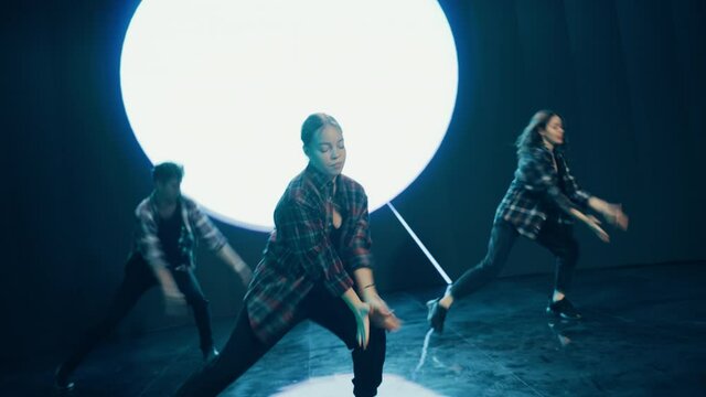 Diverse Group of Three Professional Dancers Performing a Hip Hop Dance Routine in Front of a Big Led Wall Screen with VFX Animation During a Virtual Production in Studio Environment. 105 BPM Song.
