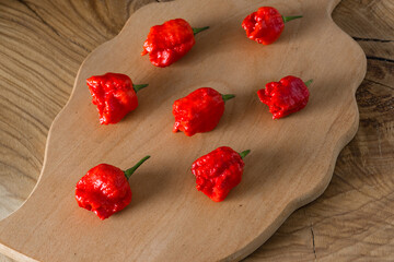 Seven pods of the world's hottest pepper of the California Reaper variety lie on a wooden board