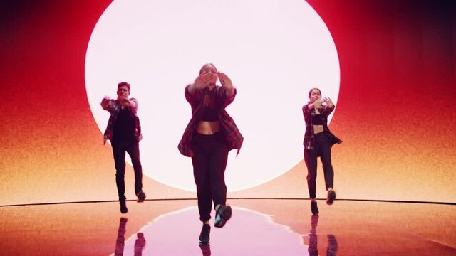 Diverse Group of Three Professional Dancers Performing a Hip Hop Dance Routine in Front of a Big Led Wall Screen with VFX Animation During a Virtual Production in Studio Environment. 105 BPM Song.