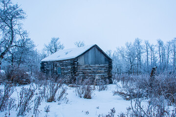 A very old and rustic log cabin in the winter in rural America.