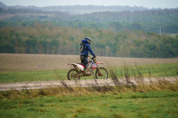 a motor cyclist (biker) riding his off-road motorbike along a stone track on Salisbury Plain, Wiltshire