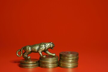 Metal tiger with coins on a red background. Financial symbol. Close-up subjects.