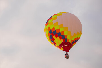 Colorful hot air balloon flying against grey sky at Winter aerostat festival. Freedom, sport, aircraft concept