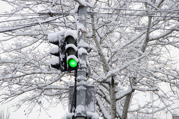 a green traffic light in winter in snow and ice in Ukraine in the city of Dnipro, roads were...