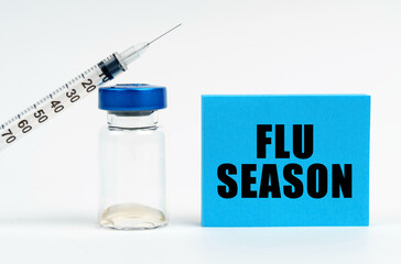 On the table is a syringe, an injection and a blue sign with the inscription - FLU SEASON