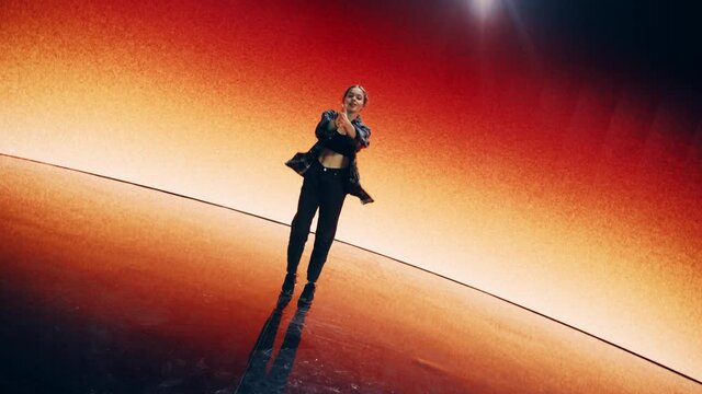 Stylish Young Professional Female Dancer Performing a Hip Hop Dance Routine in Front of Big Led Wall Screen with VFX Animation During a Virtual Production in Studio Environment. 105 BPM Song.