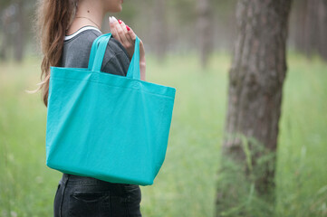 Young woman holding emerald green tote bag in park