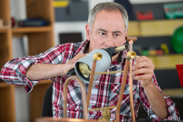 senior worker heating copper pipe with blow torch