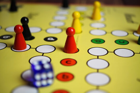 Viersen, Germany - May 9. 2021: Closeup of yellow game board with colorful pieces and dice of mensch &auml;rgere dich nicht