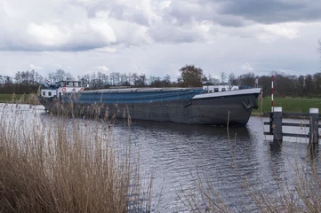 Fototapeten cargo boat maneuvers to a lift bridge in river Oude IJssel near Hoog Keppel © henkbouwers