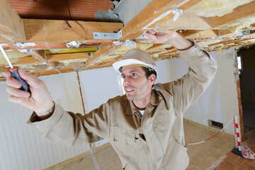 builder inspecting wooden ceiling joists - obrazy, fototapety, plakaty