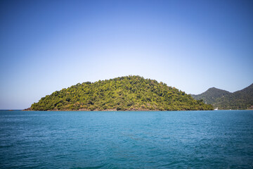 Fototapeta premium View of beautiful green island with mountain from calm sea.