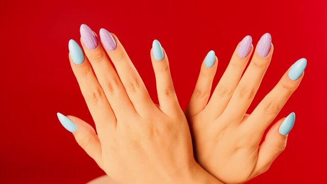 Woman's hands with beautiful nails on red background. Unrecognizable person shows manicure. Close up. Concept of care and beauty.