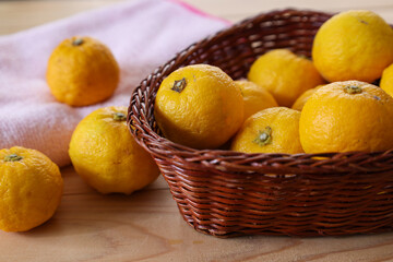 木材背景の籠にいれたユズ