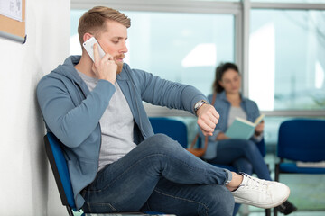 man using mobile phone in airport waiting area