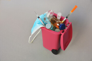 trash container with medical waste.  syringe, ampoule, vaccine,  face mask - medical pandemic items 