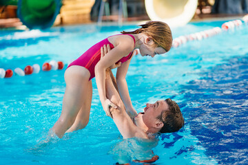 dad and daughter have fun and play in the pool. swimming training. 