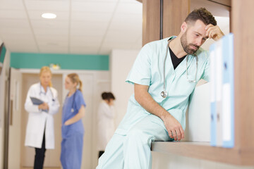 Obraz na płótnie Canvas depressed doctor sitting in corridor at hospital