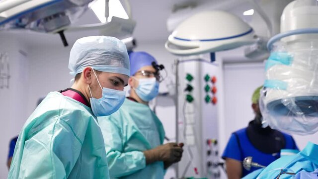 Medical professionals carrying out the operation. Surgeon chooses tools necessary for the surgery. Operation room in modern clinic.